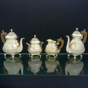 <b>Serviço para chá e café </b>em prata portuguesa decorada com gomos na base e tampa. Pés revirados, pega da tampa modelada em pinha e alças dos bules e leiteira em madeira. Contraste da cidade do Porto 916 ml usado a partir de 1938, 1º Título. Monogramado EJ. Constando de bule para café, bule para chá, leiteira e açucareiro. Alt. do bule maior 23 cm. Peso 3000 gramas.