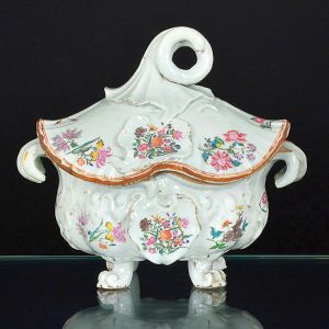 Belíssima <b>sopeira </b>oblonga em porcelana Companhia das Índias decorada em esmaltes da Família Rosa, dita "chapeau chinois", executada conforme moldes europeus. Rica policromia com cartuchos e arranjos floridos sobre fundo branco. Pegas do bojo reviradas para baixo e da tampa em enrolado. Pés revirados para cima. Séc. XVIII. Alt. 29,5 cm; Compr. 33 cm