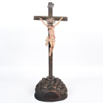 <b>ANTONIO FRANCISCO LISBOA, o ALEIJADINHO </b><br>(1738-1814)<br>Magnífico <b>crucifixo </b>em madeira, apresentando o crucificado ricamente entalhado e policromado. A imagem apresenta cuidadoso tratamento do cabelo e evidenciadas feições da dor. O monte calvário com vigorosos entalhes em diversas direções. Resplendor em prata centralizados por ametista. Séc. XVIII. Alt. 70 cm