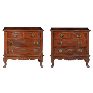 <b>Par de cômodas</b>  brasileiras em madeira nobre apresentando caixa retangular com frente movimentada. Tampo de cantos anteriores arredondados e frisados sobre duas gavetas dispostas lado a lado e outras duas gavetas de maior dimensão. Discretos entalhes em volutas e pés revirados terminados em sapatas. Ferragens em bronze de época. Séc. XIX.