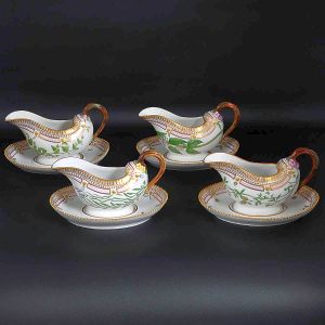 <b>Conjunto de 4 molheiras</b>, "sauce boats", com bases em porcelana dinamarquesa da importante manufatura Royal Copenhagen modelo "Flora Danica". Cada peça, inteiramente pintada à mão em belíssima policromia com suas designações botânicas e numeração no verso. Apresentam bordas em mínimos picotados cobertos a folha de ouro. Compr. 23 cm