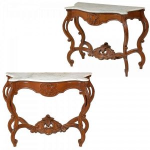 <B>Par de consoles </B>Império, estilo Luiz Felipe, com estruturas em madeiras nobres de linhas movimentadas. Entalhes em florões, volutas e vazados do estilo. Pernas e travessões inferiores em curvas e contracurvas. Tampos em mármore Carrara. Apresentam marcas de restauros nas partes inferiores. Séc. XIX. Med. 83 x 113 x 45 cm