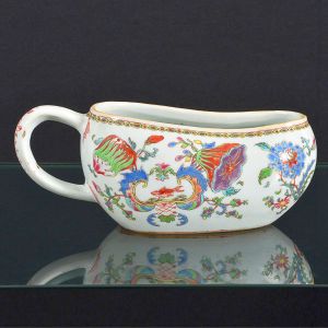 Raríssimo "<b>Bourdaloue</b>" em porcelana Companhia das Índias pertencente ao Serviço de Madame Pompadour. Decoração em rica policromia nos esmaltes da Família Rosa, com flores e frutos, destacando-se dois pares de cartuchos, um com a figura de águia sob coroa estilizada e outro com peixes. Período Qianlong. Compr. 24 cm