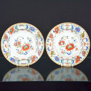 Raríssimo <B>par de pratos </B>em porcelana Companhia das Índias pertencente ao Serviço de Madame Pompadour. Decoração em rica policromia nos esmaltes da Família Rosa, com flores e frutos, destacando-se dois pares de cartuchos, um com a figura de águia sob coroa estilizada e outro com peixes. Período Qianlong. Diâm. 23 cm