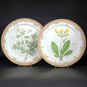 <b>Par de travessas</b>  circulares em porcelana dinamarquesa da importante manufatura Royal Copenhagen modelo "Flora Danica". Cada peça, inteiramente pintada à mão em belíssima policromia com suas designações botânicas e numeração no verso. Apresenta borda em mínimos picotados cobertos a folha de ouro. Diâm. 36 cm