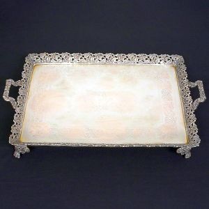 <b>Salva</b>  retangular em prata portuguesa apresentando fundo lavrado e monogramado ao centro. Borda levemente recurvada com vazado de flores e folhas. Alças decoradas com volutas e pés em garras ladeadas por botões de flor. Contrastes da cidade do Porto e marca de prateiro do séc. XIX. Med. 60 x 37,5 cm