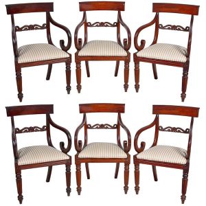 <B>Conjunto de 6 cadeiras</B>  inglesas do período William IV, construídas em mogno. Espaldar encimado por trave levemente abaulada e centro vazado com volutas. Braços enrolados para dentro, pernas anteriores gomadas e posteriores levemente recurvadas. Assento em tecido listrado. Séc. XIX. Alt. 84 cm