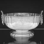 Belíssimo "<b>bowl</b>" em prata inglesa apresentando laterais em rico cinzelado com máscaras antropomorfas sustentando argola. Borda com lavrado fitomórfico. Contraste da cidade de Londres de 1916 e marca do prateiro LIONEL ALFRED CRICHTON (Crichton Brother). Med. 14 x 26 cm. Peso 1970 gramas