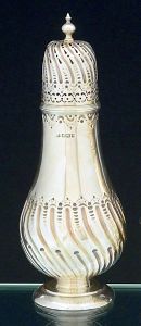 <B>Polvilhador </B>piriforme em prata inglêsa vitoriana decorada por gomos escavados e levemente torcidos na parte bojuda e tampa. Borda com arabescos. Base circular e pega da tampa modelada em pinha. Contraste da cidade de de Sheffield de 1891 e marca do prateiro ATKIN BROTHERS. Alt. 23 cm