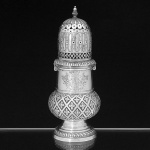 Belíssimo <b>polvilhador </b>em prata holandesa brasonada. Parte inferior bojuda decorada com trevos, brasão lavrado ao centro e base em gominhos retorcidos. Pega da tampa em modelado de pinha. Contraste usado a partir de 1814 até 1953 e marca de prateiro. Alt. 22,5 cm. Peso 450 gramas.