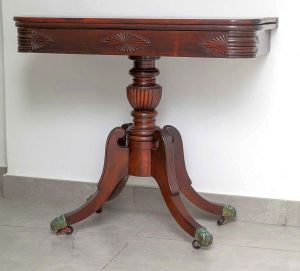 <B>Console</B>  império brasileiro de forma retangular, em madeira nobre, reversível p/ mesa de jogo.  Quinas anteriores arredondadas e caneladas. Montante central na forma de balaústre gomado, pernas recurvadas e pés em garras metálicas sobre rodinhas. Séc. XIX. Med. 78 x 88 x 43 cm