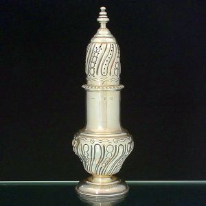 <b>Polvilhador </b>de formato balaústre em prata inglesa vitoriana, decorado com gomos levemente torcidos intercalados por elementos circulares. Base redonda e pega modelada em pinha. Contraste da cidade de Birmingham de 1878. Prateiro P&C. Mossa em uma lateral. Alt. 26,5 cm