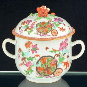 "<b>Porringer" com tampa </b>ou açucareiro em porcelana Companhia das Índias, ricamente decorado em policromia numa variação do padrão "Folha de Tabaco", conhecida como "Folha de Chá". Pega da tampa em modelado de flor em "rouge de fer". Séc. XVIII. Compr. sem as alças 15 cm