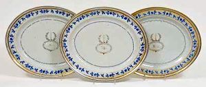 <b>Conjunto de três travessas </b>de forma oval, em porcelana Companhia das Índias, período Jiaqing, tendo ao centro "crest" monogramado, perolados e bordas com cachos de uvas e folhas de parreira em azul índigo realçados a ouro. Início do séc. XIX. Med. 40,5 x 34 cm