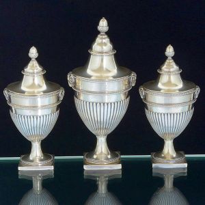 <b>Conjunto de 3 "confituriers" </b>em prata inglesa, com timbre armorial e decoração com gomos e perolados. Laterais com cabeça de carneiros e pegas modeladas em pinha. Contrastes georgeanos de Londres de 1817 e marcas de prateiro. Alt 22 cm e 17 cm. Peso 960 gramas.