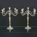 <b>Par de candelabros para cinco velas</b>, reversíveis em castiçais, em prata portuguesa. Apresenta braços em serpentina, haste e base gomadas. Monograma E J na base. Contraste "Águia", 1º Título, 916 ml, usado de 1886 a 1938. Alt. 47 cm. Peso 4805 gramas.