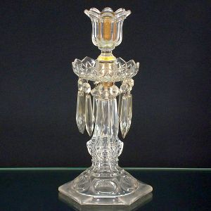 <b>Castiçal </b>em cristal, provavelmente Baccarat, apresentando base hexagonal com elementos ovoides, haste em segmento de balaústre e "bobèche" centralizada com ponteiras pendentes. Receptáculo em forma de floráceas. Séc. XIX. Alguns bicados. Alt. 32 cm