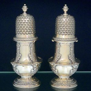 <b>Par de polvilhadores </b>em prata inglesa decorada em estilo fitomórfico e cabeças de anjos. Bases e borda da tampa peroladas e pega em forma de pinha. Contraste da cidade de Londres de 1900 e marca do prateiro JOSHUA VANDER. Alt. 24 cm. Peso 1135 cm.