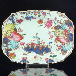 <b>Travessa </b>de forma retangular com cantos chanfrados em porcelana Companhia das Índias decorada em policromia no conhecido padrão "Folha de Tabaco", apresentando figura de "Guanyn" cercada por rica policromia florida. Séc. XVIII. Compr. 30 cm