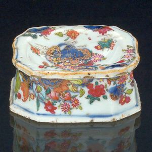 <B>Saleiro </B>de forma retangular com cantos chanfrados em porcelana Companhia das Índias decoradas em policromia no conhecido padrão "Folha de Tabaco", apresentando figura de "Guanyn" cercada por rica policromia florida. Séc. XVIII. Compr. 8 cm