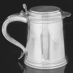 "<b>Tankard</b>" em prata inglesa, em forma de barril, com corpo e tampa lisos com frisos na base e borda. Alça recurva terminada em coração. Contraste da cidade de Londres de 1905 e marca do prateiro H. S. LD. Alt. 17,5 cm. Peso 1045 gramas.