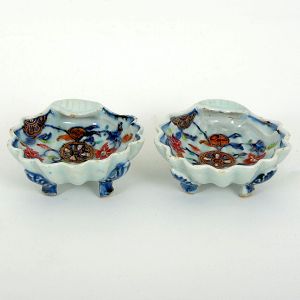 Raro <b>par de saleiros </b>em forma de "coquilles" em porcelana Companhia das Índias decorada em policromia da Família Rosa numa variação do padrão "Folha de Tabaco", conhecida como "Folha de Chá". Séc. XVIII. Compr. 10 cm; Larg. 3 cm