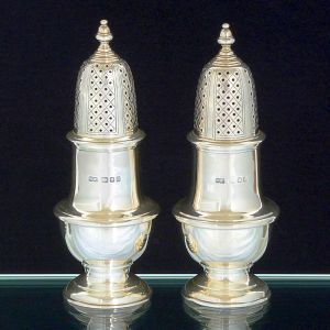 <b>Par de polvilhadores </b>em forma balaústre lisa, em prata inglesa, com bases circulares e pega das tampas modeladas em pinha. Contraste da cidade de Londres de 1961 e marca do prateiro MAPPIN & WEBB. Alt. 16,5 cm. Peso 435 gramas.