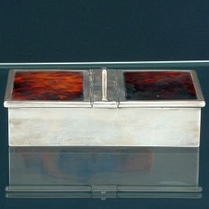 <B>Caixa retangular para cigarros </B>em prata inglesa. Apresenta duas tampas rebatíveis revestidas em tartaruga e alça ao centro. Contraste da cidade de Londres de 1926 e vestígio da casa MAPPIN & WEBB. Compr. 19 cm; Alt. 4,5 cm