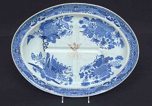 <B>Travessa </B>oval para assados em porcelana Companhia das Índias decorada em azul índigo no padrão "Fitzhugh" feito de encomenda para o mercado americano. Ao centro monograma sob timbre. Início do séc. XIX. Med. 44,5 x 34 cm
