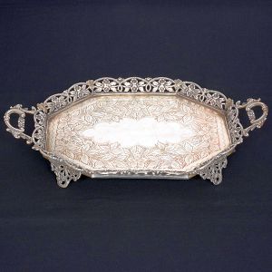 <B>Bandeja </B>octogonal em prata portuguesa com fundo lavrado e aba em chanfrados vazados e floridos. Pés no estilo. Contraste da cidade do Porto de meados do séc. XIX e marcas de prateiro. Med. 40,5 x 24 cm. Peso 3160 gramas.
