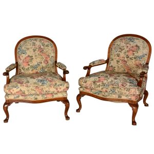 Antigo <b>par de cadeiras de braços </b>inglesas, com assento avantajado e estrutura em mogno. Braços sinuosos terminados em enrolados e pernas recurvadas terminadas em sapatas. Belo estofamento em tecido decorado com frutos.