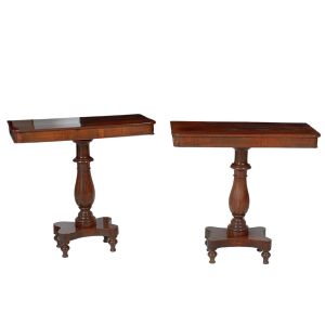 <b>Par de consoles </b>em madeira nobre apresentando tampos retangulares apoiados em hastes centrais torneadas em segmentos de balaústre e assentadas em "plateau" de movimento ondulatório. Pés em fusos torneados. Séc. XIX.