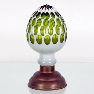 <b>Pinha </b>em cristal, ornamentada em "overlay" verde translúcido, trabalhada com sucessivas aberturas ovais que revelam o tom interno. Corpo de forma arredondada, apoiado sobre base em latão envelhecido. Alt. 22 cm