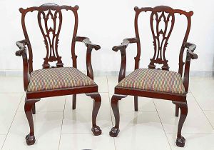 <b>Par de cadeiras </b>no estilo Chippendale construídas em mogno. Encosto em estilizações vazadas, braços movimentados e pernas recurvadas terminadas em garras sobre esferas. Assento em tecido. Alt. 101 cm
