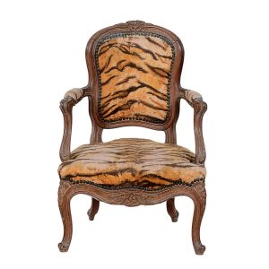 Pequena e antiga <b>cadeira baixa </b>europeia com estrutura em madeira clara de movimentos ondulatórios. Delicados entalhes de flores, pernas recurvadas e estofamento em "animal print". Alt. 66 cm