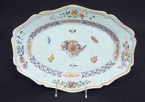 <B>Travessa </B>oblonga em porcelana Companhia das Índias decorada em policromia Família Rosa com brasão ao centro circundado por insetos. Borda recortada e florida. Séc. XVIII. Med. 36,5 x 28 cm
