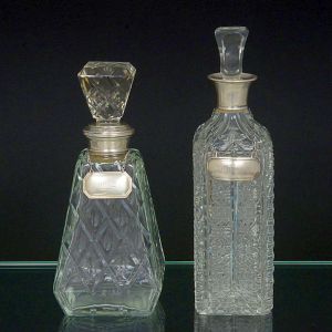 <b>Conjunto composto por duas garrafas </b>em cristal transparente finamente lapidado, cada uma com padrão geométrico distinto. Acompanham plaquetas em metal com as inscrições "Port" e "Whisky".