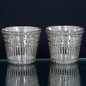 <b>Par de "cachepots" </b>em prata, trabalhados em finos recortes vazados de desenho geométrico e floral. Bordas e bases decoradas com frisos entrelaçados. Marca do prateiro ilegível. Alt. 8 cm