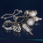 <B>Balangandã </B>em prata baiana com diversas e robustas frutas tropicais, pandeiro e atabaque. Cadeado ladeado por pombas e corrente em elos. Prateiro GERSON. Compr. 19 cm. Peso 425 gramas.