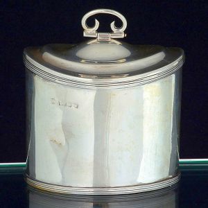 "<b>Tea-caddy</b>" em prata inglesa lisa com bojo frisado nas bordas e pega da tampa em elemento vazado. Contraste da cidade de Birmingham de 1920. Alt. 9,5 cm; Compr. 9 cm. Peso 150 gramas.