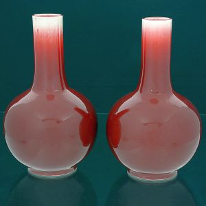 <b>Par de vasos </b>bojudos de gargalos longos e cilíndricos em porcelana chinesa decorada em esmalte sangue de boi. Ideograma no fundo. Acompanham bases em madeira. Alt. sem as bases 29 cm