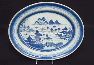 <B>Travessa </B>oval para assados em porcelana chinesa do séc. XVIII, decorada em azul índigo "underglaze" com paisagem lacustre e casario. Borda em arabescos. Séc. XVIII. Med. 41,5 x 34 cm