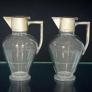 <b>Par de jarras </b>bojudas em cristal inglês liso com montagem em prata vitoriana. Tampa monogramada e base estrelada. Contraste da cidade de Birmingham de 1890 e marca do prateiro H&P.