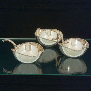 <b>Conjunto de 2 porta petiscos</b>, sendo um deles duplo, em metal espessurado a prata com borda em frisos torcidos e alças com detalhes em pequenos frutos. Sem marca. Compr. 28 e 18 cm