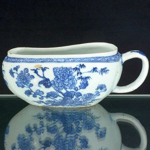 "<b>Bourdaloue</b>" em porcelana Companhia das índias decorada com arranjos floridos e arabescos em azul índigo "underglaze" sobre fundo branco. Séc. XVIII. Alt. 10,5 cm; Compr. 25 cm