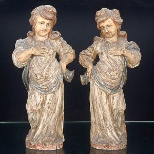 <b>Par de estatuetas </b>de figuras infantis, de postura graciosa, em madeira entalhada, com vestígios de policromia original em tons suaves. Europa, séc. XVIII / XIX. Alt. 47 cm