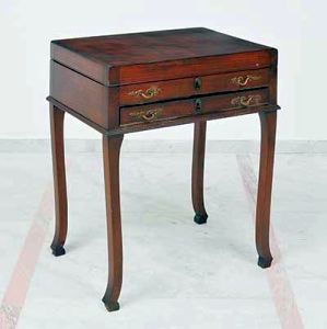 Antiga <b>mesa auxiliar</b>, provavelmente europeia, construída em madeira nobre. Duas gavetas anteriores com ferragens metálicas e pernas levemente recurvadas com rodinhas.