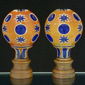 <B>Par de pinhas </B>globulares francesas em cristal azul com "overlay" em âmbar e branco. Lapidação com círculos e elementos estrelados. Base em bronze. Séc. XIX. Alt. 16 cm