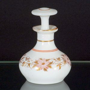 <B>Pequeno frasco </B>em vidro opalinado branco, de corpo bojudo e gargalo alongado, acompanhado de tampa. Apresenta decoração floral policromada em tons de rosa e dourado.