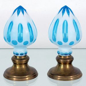 <b>Par de pinhas </b>em cristal, ornamentadas em "overlay" azul claro, com cortes verticais e circulares revelando a camada interna. Base circular em metal dourado.